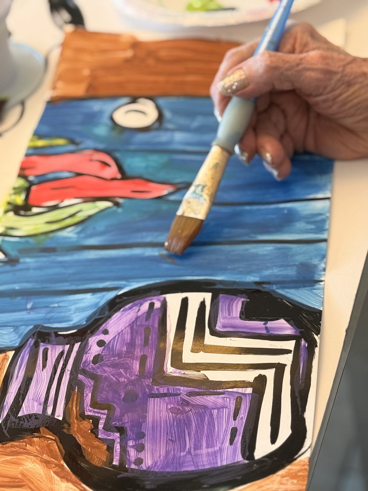 A resident painting a colorful art project at Hacienda De Luna